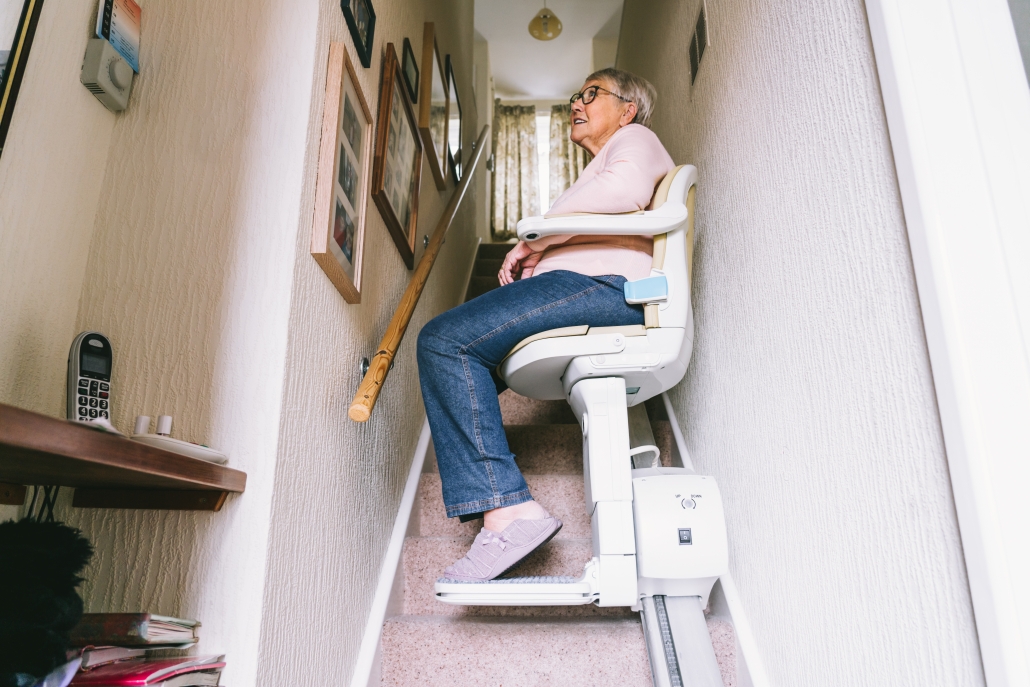 Una persona anciana usa una silla salvaescaleras en su hogar.
