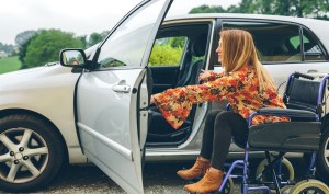 Mujer en silla de ruedas subiendo a su coche adaptado.